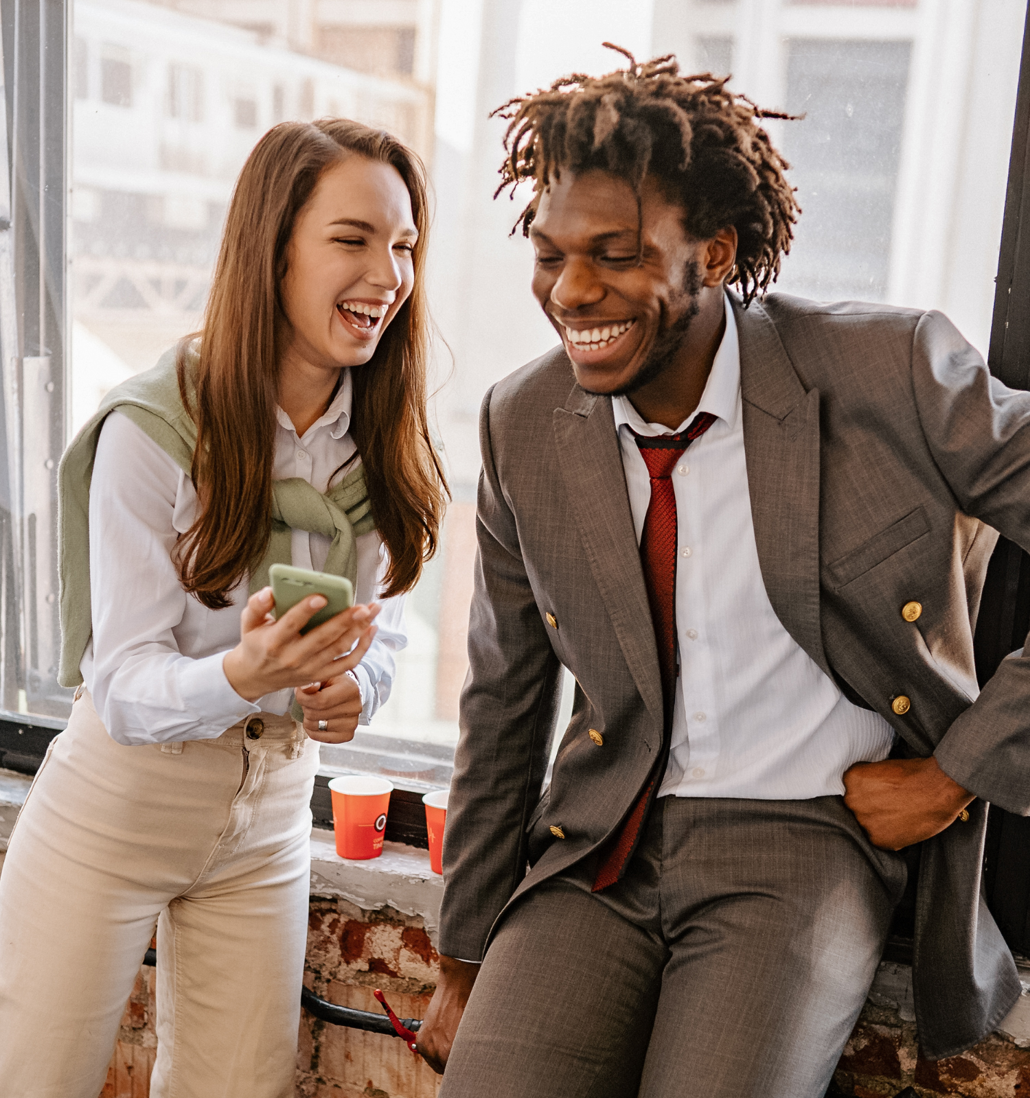 Two people smiling while looking at a phone together